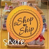 A candy display is covered by an orange ornament that reads "Shop Not Ship - Share."
