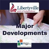 The background is dark blue. In the center is a photo of two hands pointing at a map. At the top center is an American flag in the shape of an L next to text that reads "Libertyville - Spirit of Independence." Text overlay on the photo says "Major Developments."