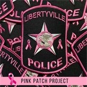 The background is a stack of pink and black police patches. There is a light pink section at the bottom with text that says "Pink Patch Project" next to a pink breast cancer awareness ribbon.