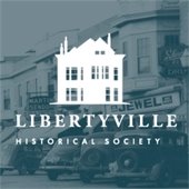 A vintage photo of cars and shops is in a blue hue. Text reads "Libertyville Historical Society."