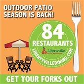 A patio umbrella and two chairs are on an orange background next to a large silver fork with the headline "Patio season is back!" In a bright green circle reads "84 restaurants - LibertyvilleDining.com"