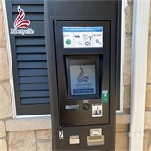 A photo of a payment kiosk for parking spaces. In the top left corner is a logo resembling the American flag in the shape of an L that says "Libertyville."
