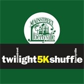 The background is dark green. Text is within a black rectangle and reads "MainStreet Libertyville Twilight 5K Shuffle."
