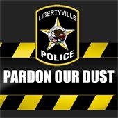 Caution tape says "Pardon our dust" over a dark gray background. At the top center is an illustration of the Libertyville Police Department logo.