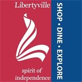 The background is red on the left and dark blue on the right. In the center is a white L with the text "Libertyville: Shop. Dine. Explore."