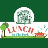 In the center of the image is a colorful display of trees, a picnic table, and music notes that says "Lunch in the Park." Above is a green logo that reads "MainStreet Libertyville."
