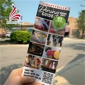 A hand holds a brochure with a cover full of food photos.